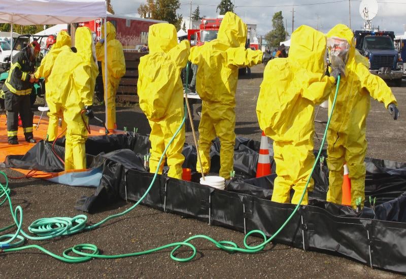 Worker in Protective Gear Performing Industrial Cleaning in a Factory